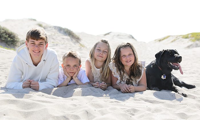 Dennis standing on a field with his wife and two kids.