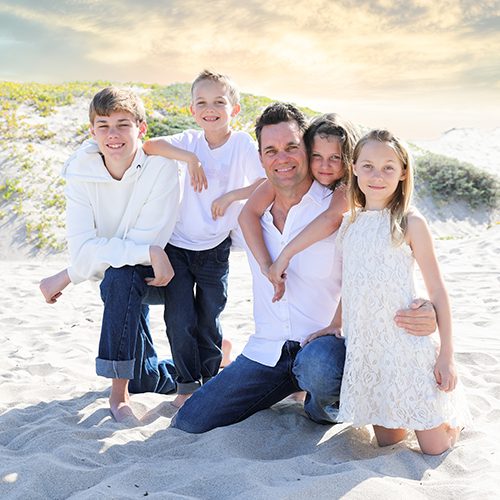 Dennis sitting on a bench with his wife and two kids.