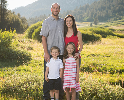 Dennis standing on a field with his wife and two kids.