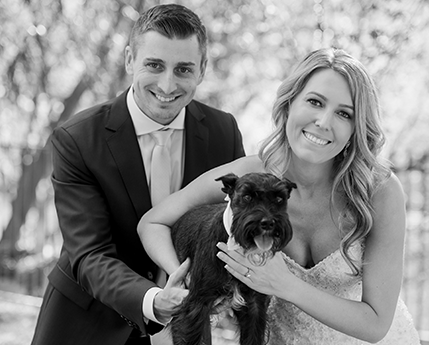 Amy posing on her wedding day with her husband and dog.